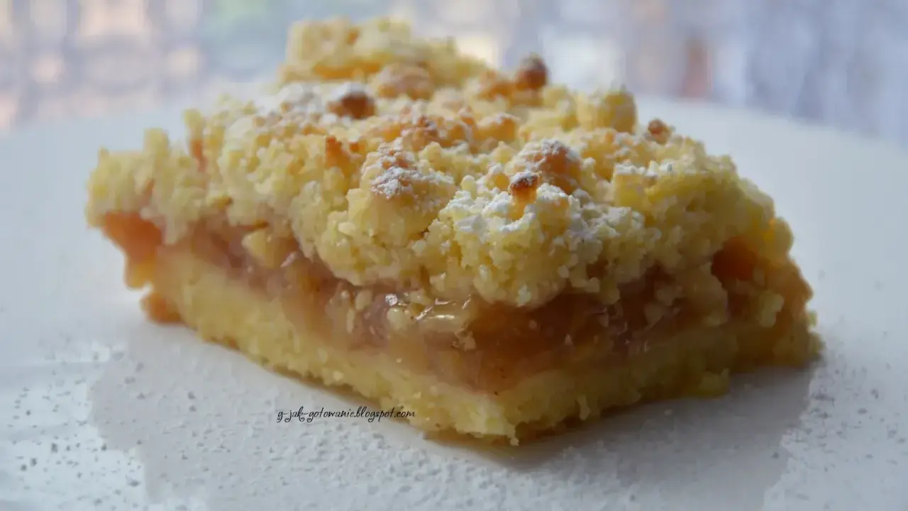 Pyszna tarta z jabłkami, posypana cukrem pudrem, kusi chrupiącą kruszonką i aromatycznym nadzieniem.