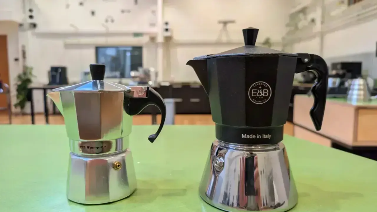 Zwei Espressokocher, ein silberner und ein schwarzer, stehen bereit für den perfekten Espresso auf dem Herd.
