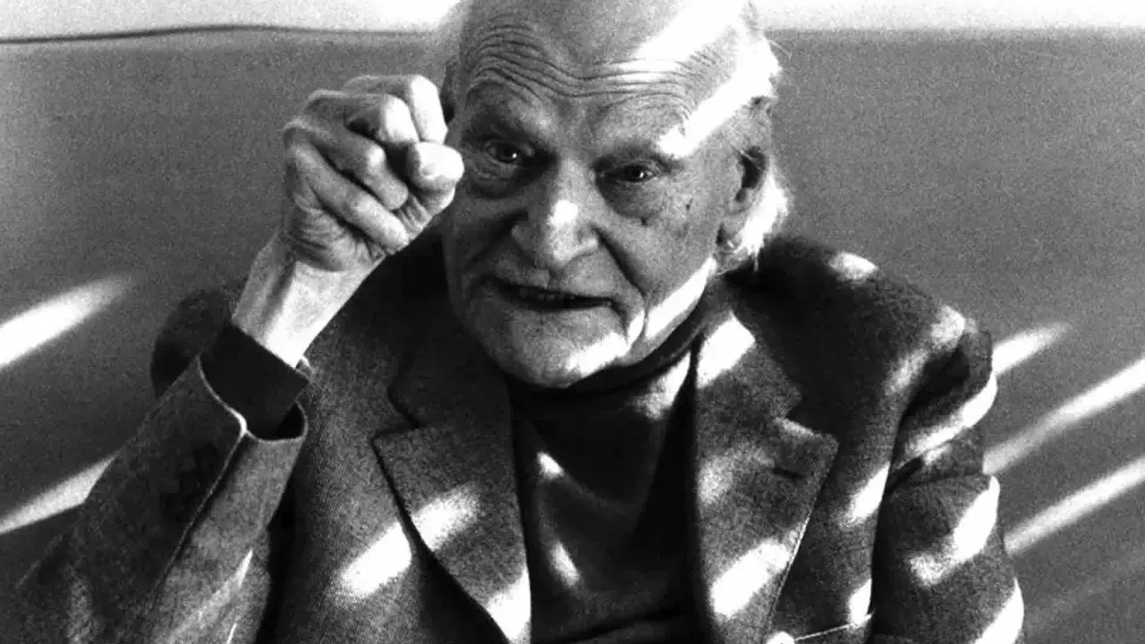Ritratto di un anziano con pugno alzato, in memoria di Ungaretti. Le rughe sul volto e la luce che lo illumina creano un'atmosfera intensa.