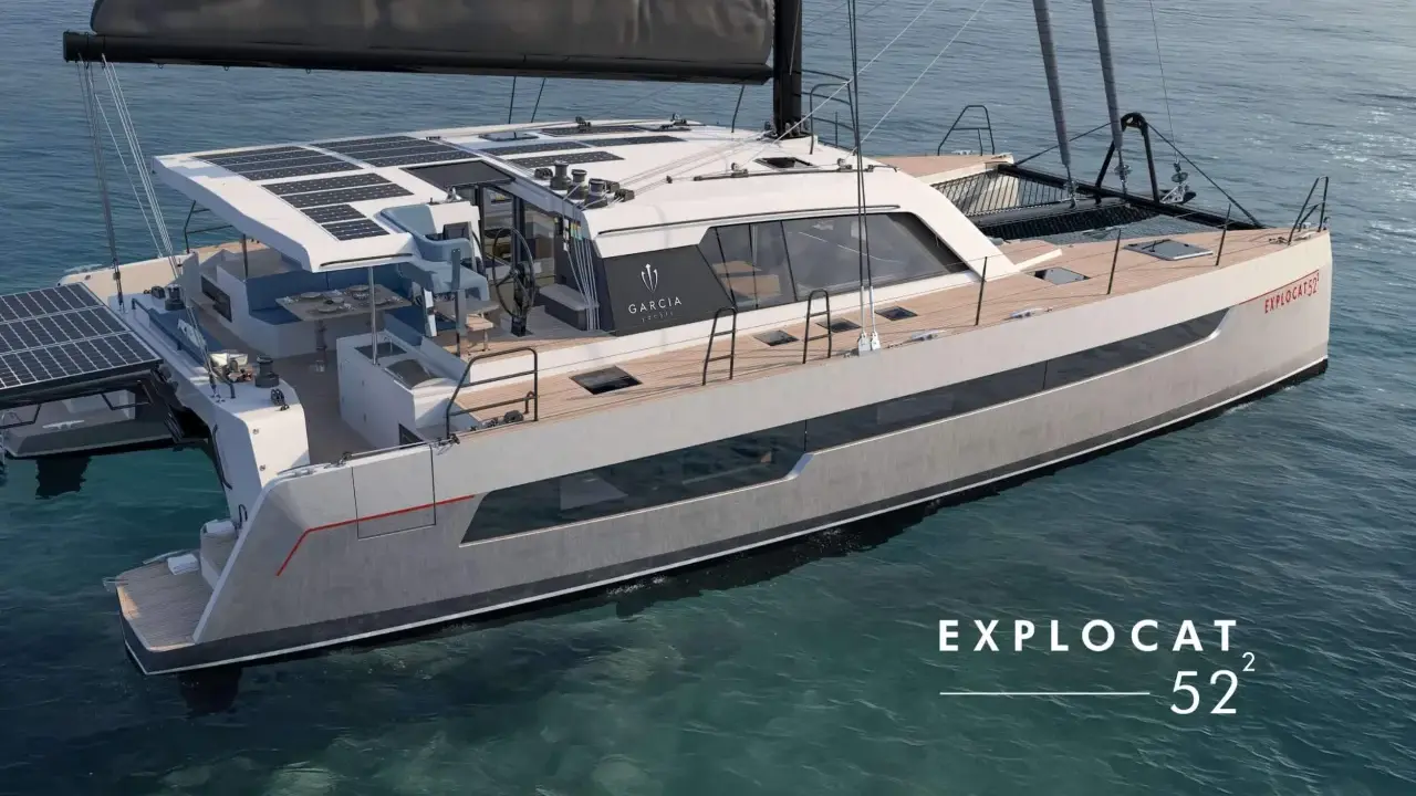 Un catamaran de luxe, un **deriveur integral** moderne, navigue sur des eaux bleues claires. Panneaux solaires sur le toit, design épuré.