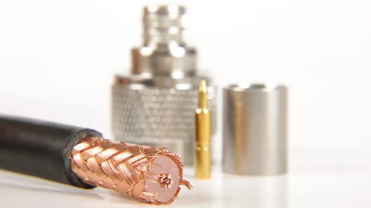Przewód ekranowany z miedzianym oplotem, obok złoty pin i metalowe złącza.