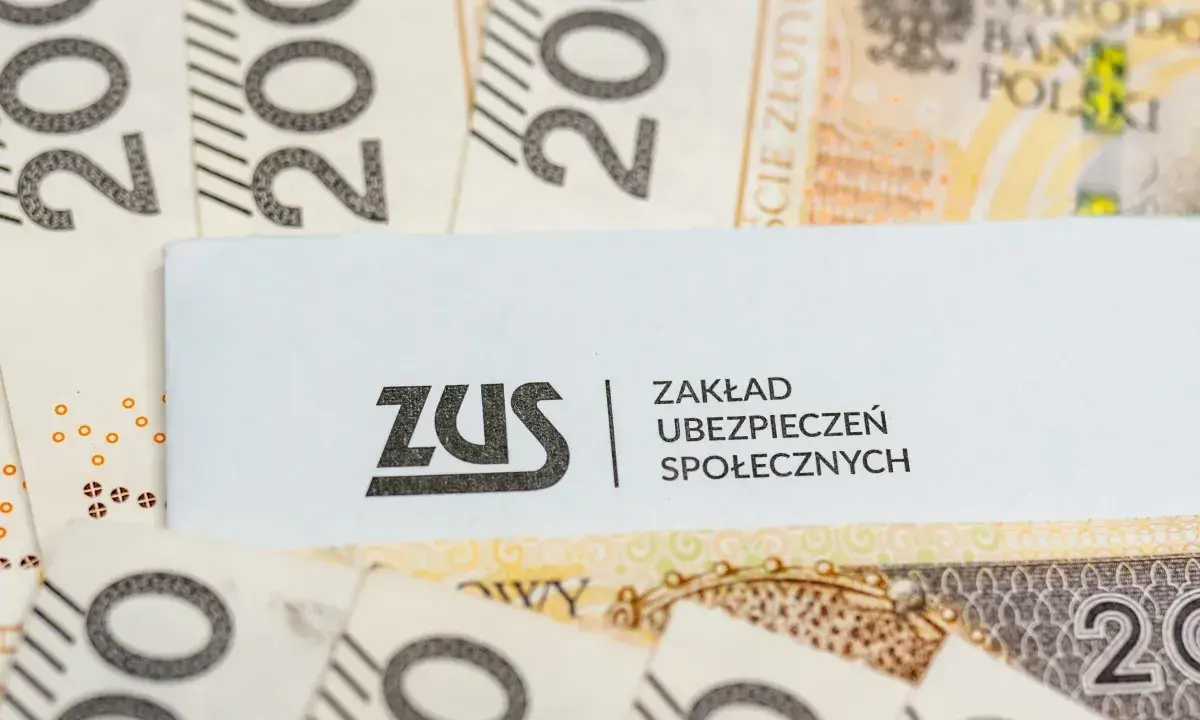 Logo ZUS na tle polskich banknotów 200 zł.