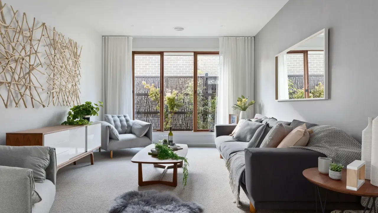 Elegante salón donde el gris y beige combinan a la perfección, con sofás cómodos, mesa de centro de madera y una original decoración de ramas en la pared.