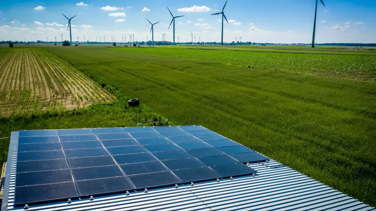 Panele słoneczne na dachu i wiatraki na polu, symbolizujące program agroenergia i zrównoważony rozwój.