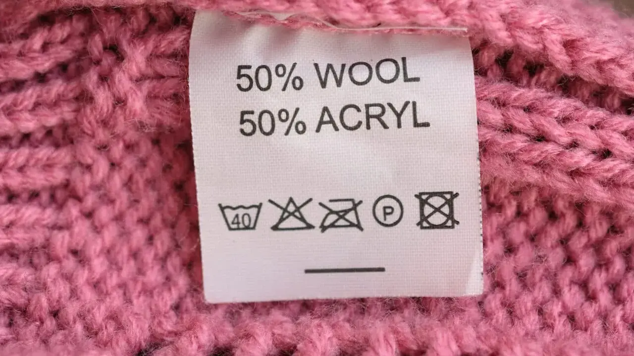Tvättråd på en rosa stickad tröja: 50% ull, 50% akryl. Kan indikera nackdelar med ull som känslighet för höga temperaturer.