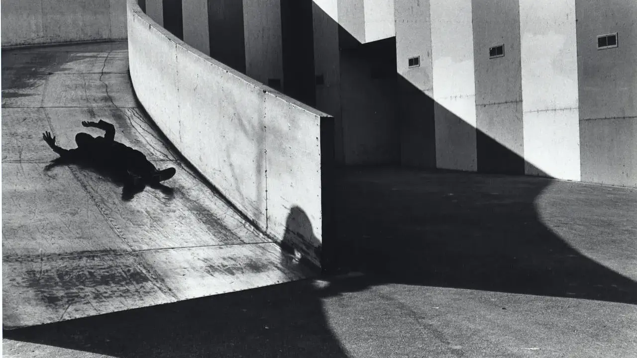 A silhouetted figure lies on a curved concrete ramp, arms outstretched, at the Janet Borden Gallery.