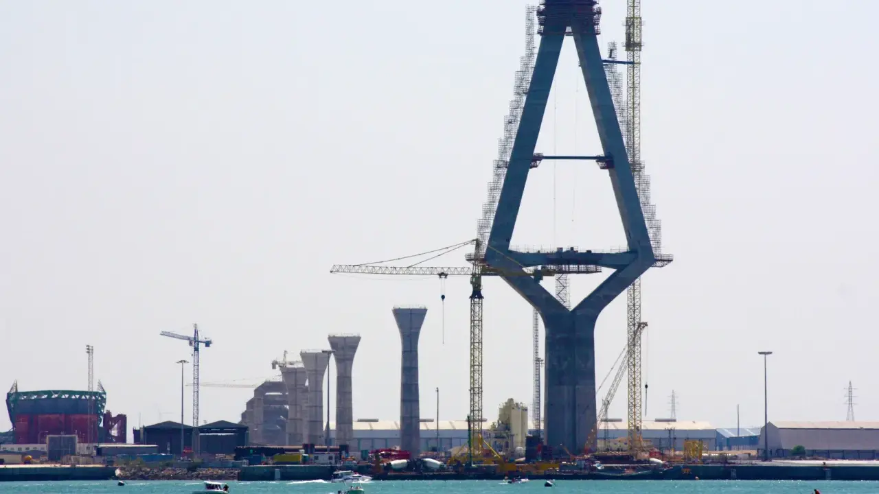 Construcción de un puente con pilares de hormigón y grúas, sobre el mar.