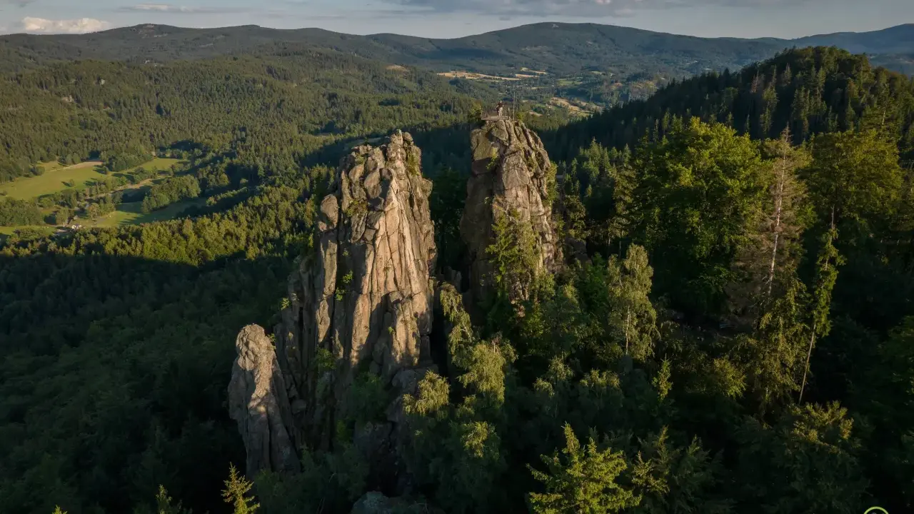 Skaliste szczyty, jak sokolik duży, górują nad lasem. Na jednym z nich platforma widokowa z turystą.