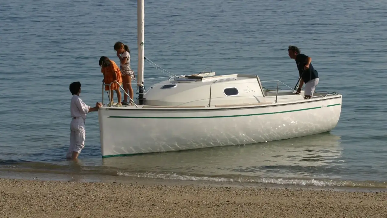 Une famille prépare son voilier, icône 6, pour une sortie en mer. Les enfants montent à bord, impatients de naviguer.