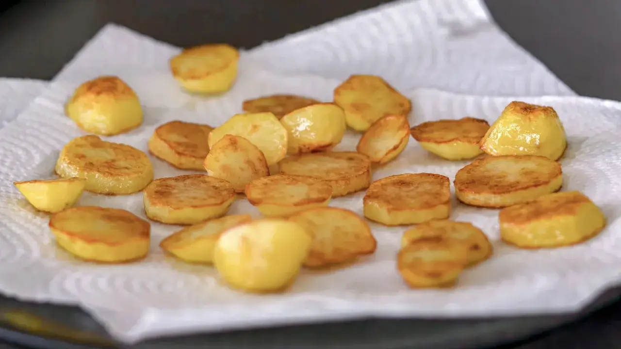Rodajas de patatas al horno, doradas y crujientes, reposando sobre papel absorbente. ¡Listas para disfrutar!