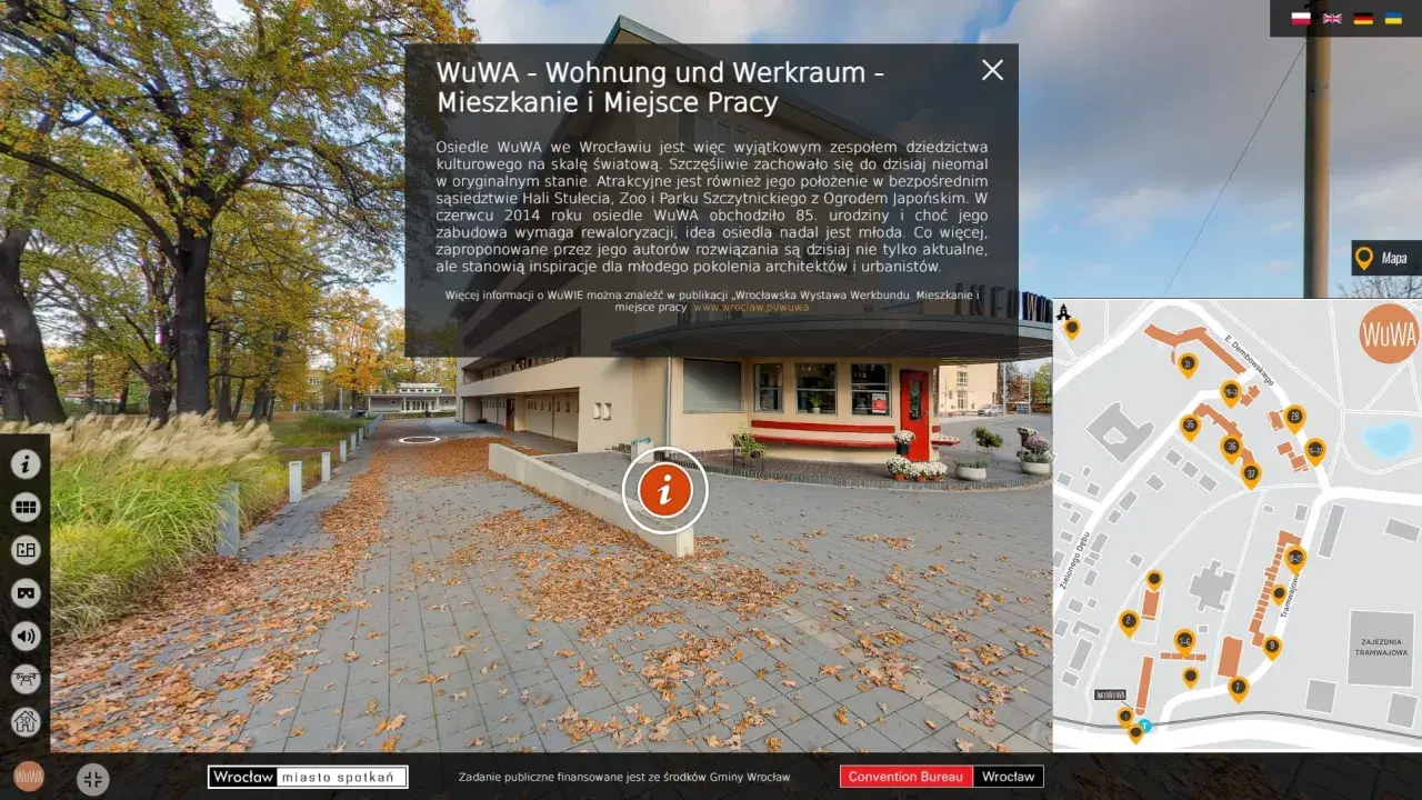Jesienne liście na chodniku przed osiedlem WuWA we Wrocławiu. W tle budynek i drzewa. Mapa pokazuje rozmieszczenie budynków.