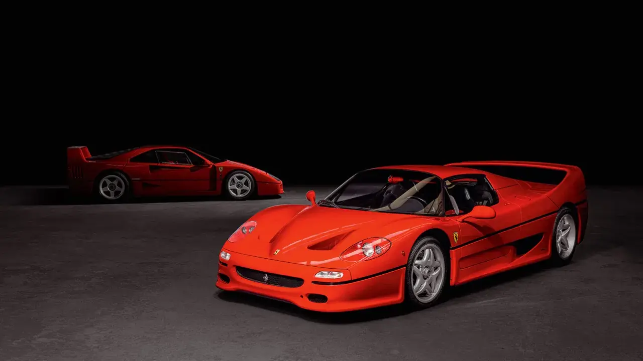Zwei rote Ferraris, ein F50 und ein F40, stehen nebeneinander auf dunklem Grund.