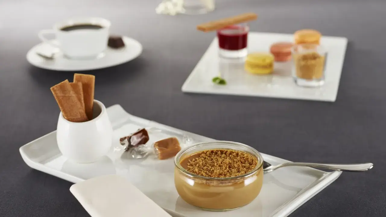 Un café gourmand avec diverses mignardises : verrine caramélisée, macarons, biscuits, chocolats. Idéal pour des recettes de mignardises pour café gourmand.