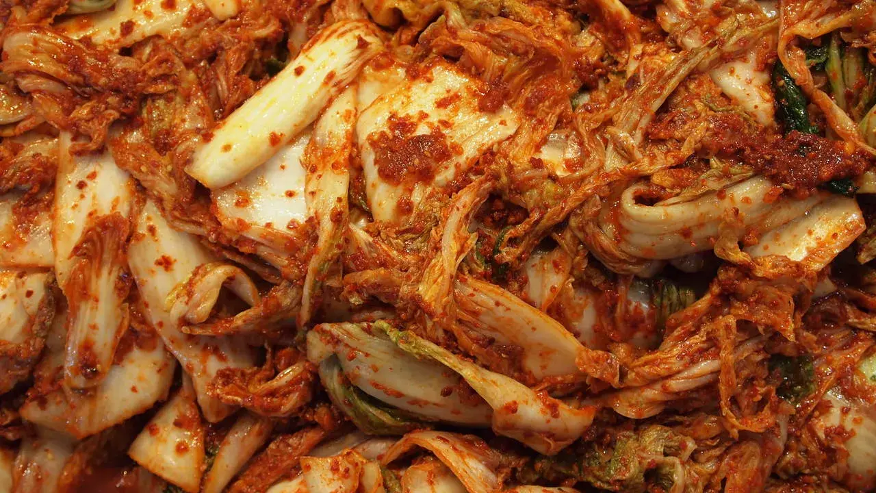 Zbliżenie na świeże, pikantne kimchi z kapusty pekińskiej, pokryte czerwoną pastą chili.