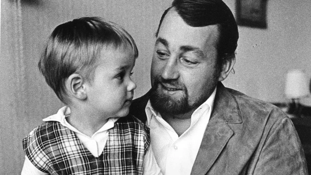 Cornelis Vreeswijk med sitt barn i en rutig väst. En varm stund mellan far och son.