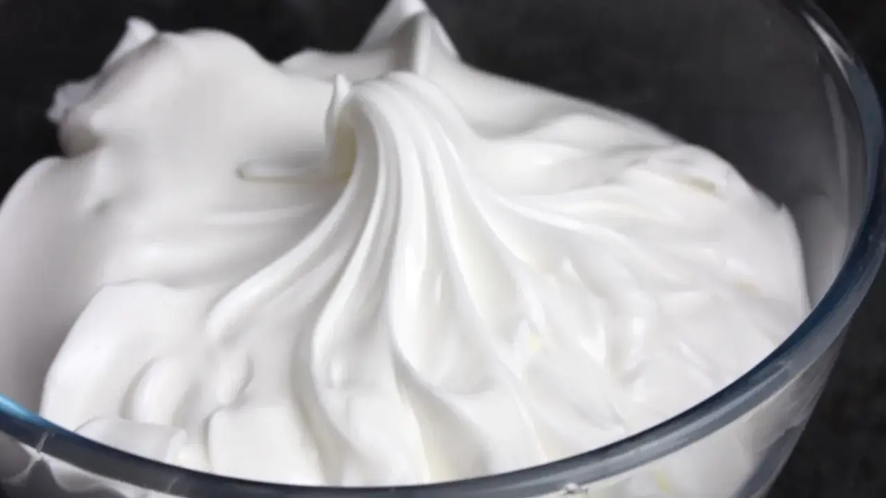 Merengue italiano esponjoso y brillante en un bol de cristal, listo para decorar postres.