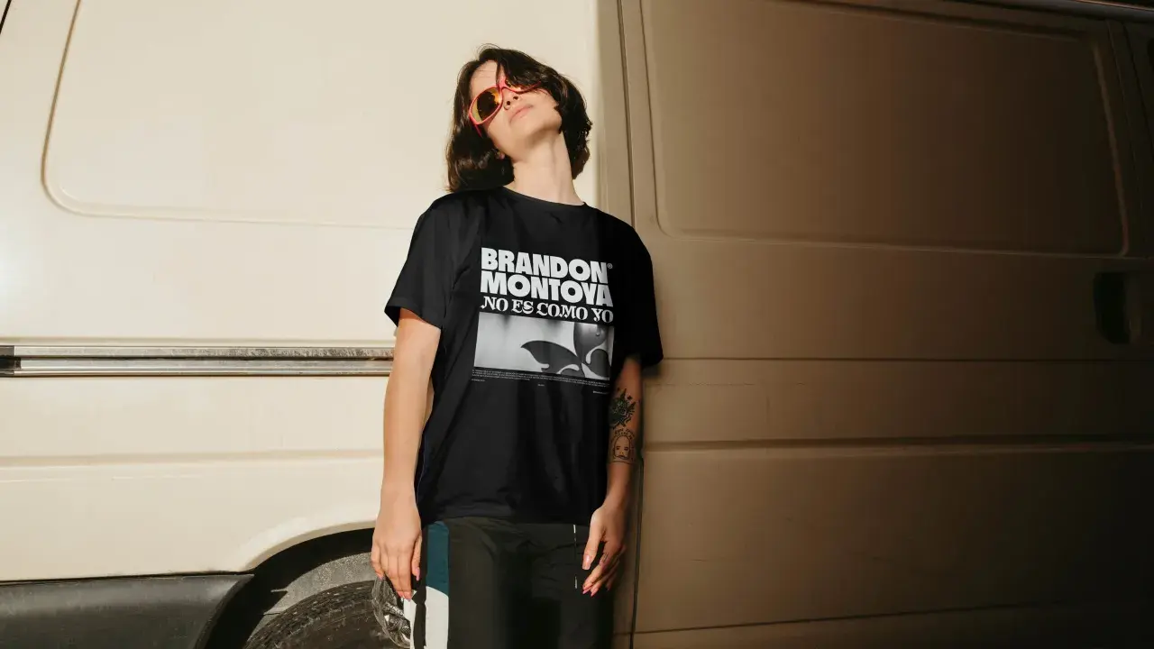 Joven con gafas de sol naranjas y camiseta negra con el diseño "BRANDON MONTOYA NO ES COMO YO".