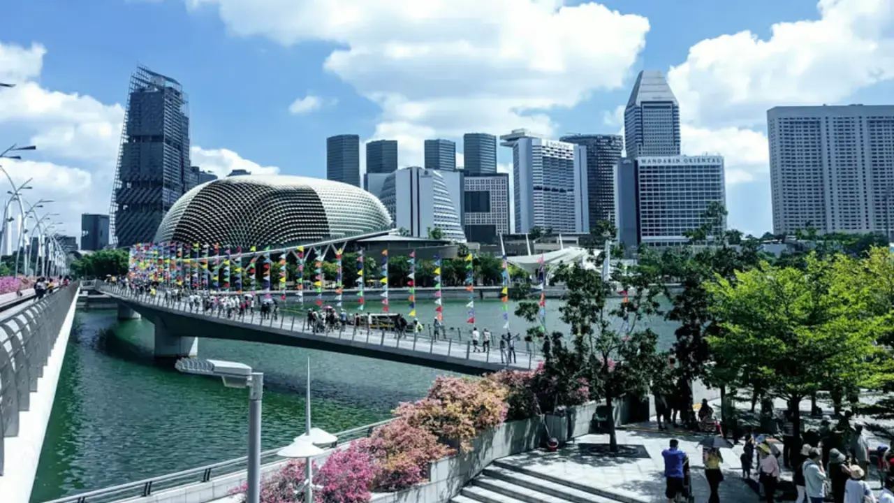 Fakta om Singapore: En bro med flaggor leder mot en futuristisk skyline med Esplanade-teatern.