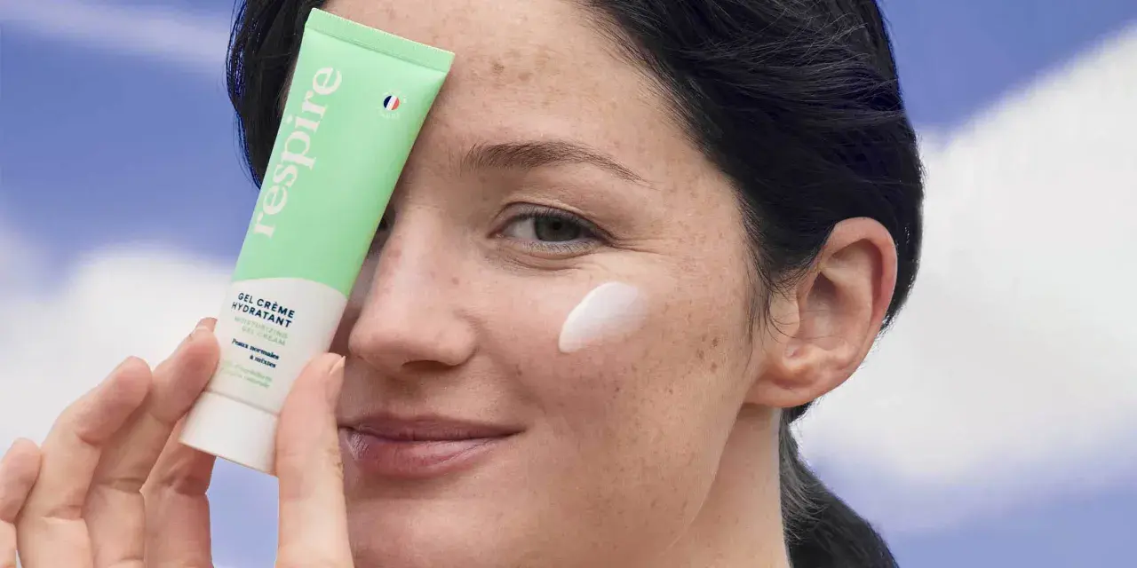 Une femme applique une crème hydratante sur sa joue. Une solution pour comment hydrater sa peau très sèche.