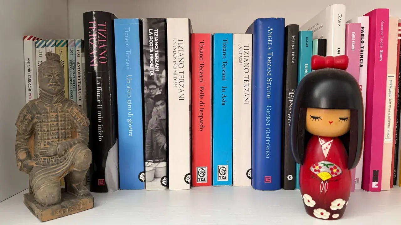 Statua guerriero terracotta e una collezione di libri di Tiziano Terzani, tra cui "La fine è il mio inizio" e "Un altro giro di giostra".