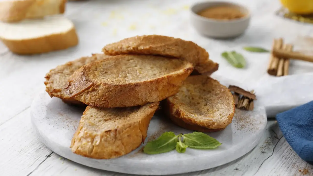 Torrijas al horno doradas y crujientes, espolvoreadas con canela, listas para disfrutar.