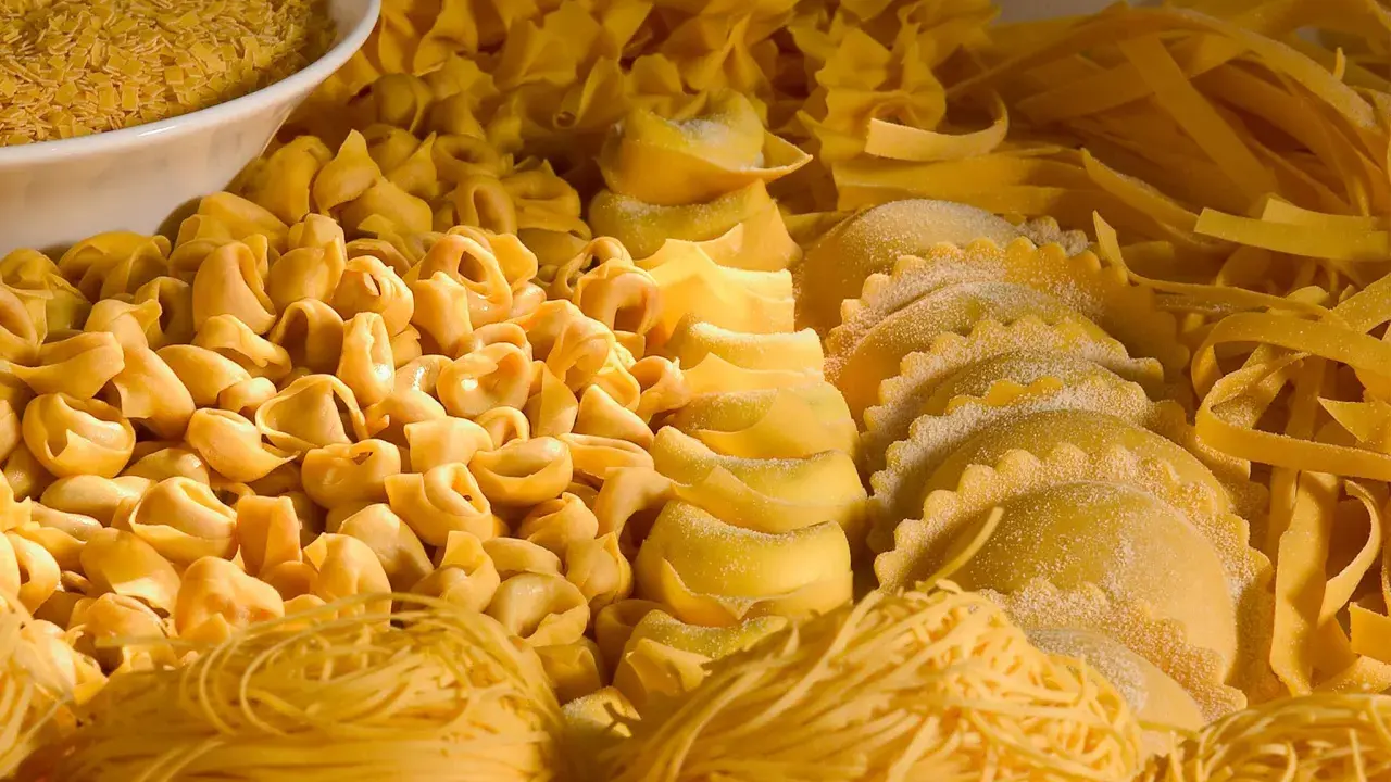 Varietà di pasta fresca, tra cui tortellini, ravioli e tagliatelle, che rappresentano i piatti tipici dell'Emilia Romagna.