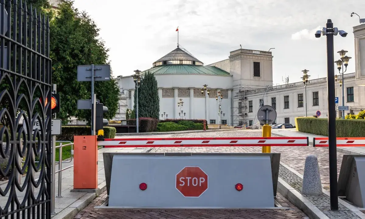 Brama wjazdowa do Sejmu, symbolizująca immunitet poselski, z barierą i znakiem STOP.