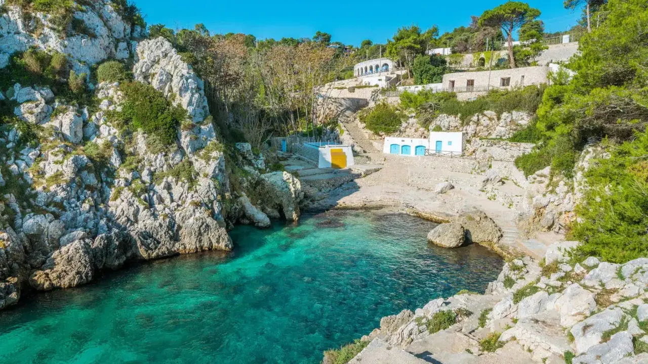 Baia incantevole con acque cristalline, perfetta per un itinerario Puglia 3 giorni. Case bianche e rocce a picco sul mare.