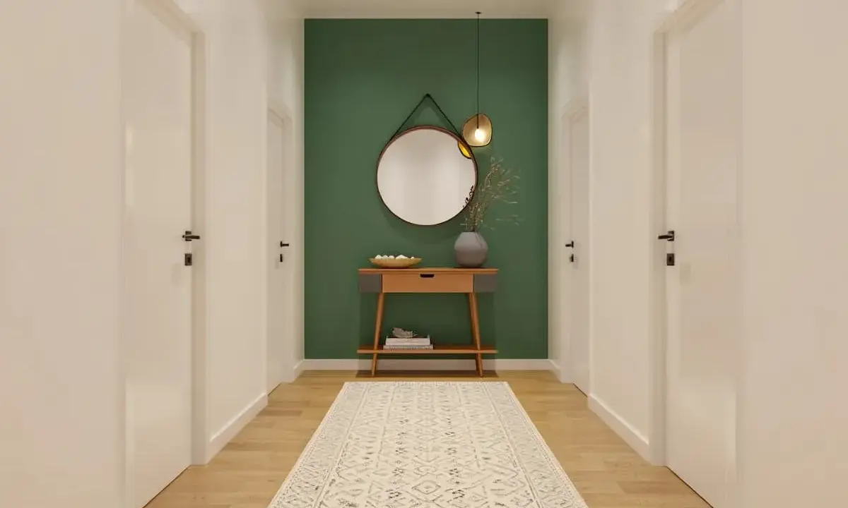 Un couloir moderne avec un mur vert, un miroir rond, une console en bois et un tapis. Une belle idée déco couloir moderne.