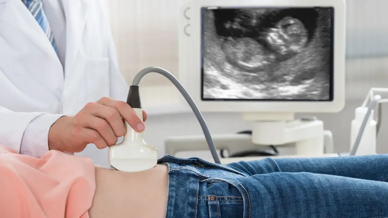 Lekarz wykonuje USG. Na ekranie widać zarodek, to 11 tydzień ciąży, który to miesiąc rozwoju dziecka.