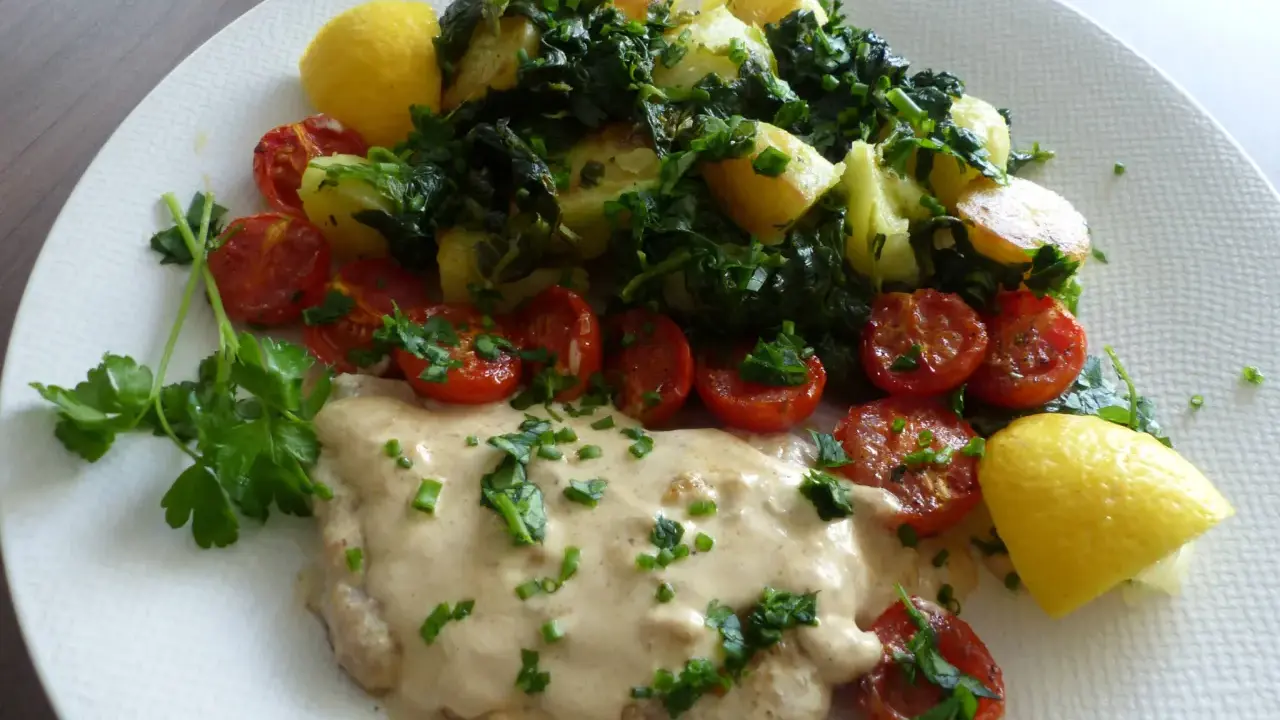 Escalope de veau crémeuse, accompagnée de pommes de terre sautées, tomates cerises rôties et quartiers de citron.