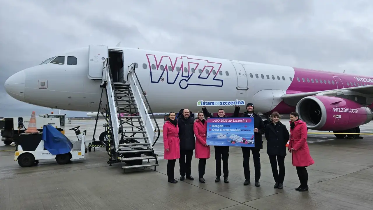 Grupa osób pozuje przed samolotem Wizz Air, trzymając tablicę z informacją o nowych trasach, w tym lotach Szczecin-Bergen.