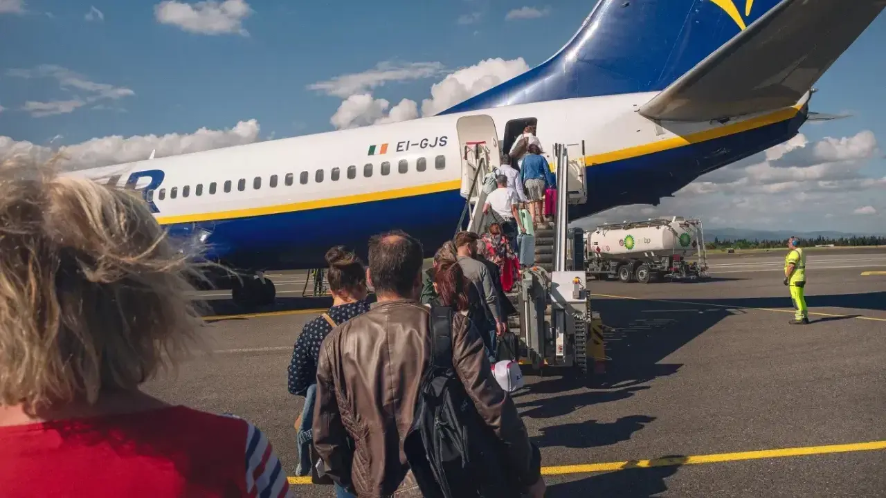 Pasażerowie wsiadają do samolotu Ryanair. Zastanawiasz się, ile kosztuje odprawa na lotnisku? Tutaj nie ma dodatkowych opłat.