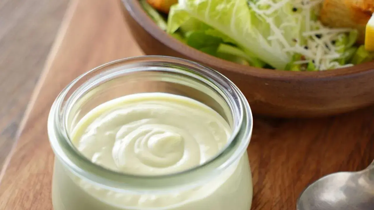 Cremiges Dressing in einem Glas, bereit für einen köstlichen veganen Caesar Salad mit Croutons und Parmesan-Alternative.