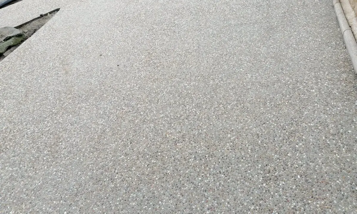Superficie de hormigón desactivado con pequeñas piedras incrustadas, creando una textura rugosa y antideslizante.