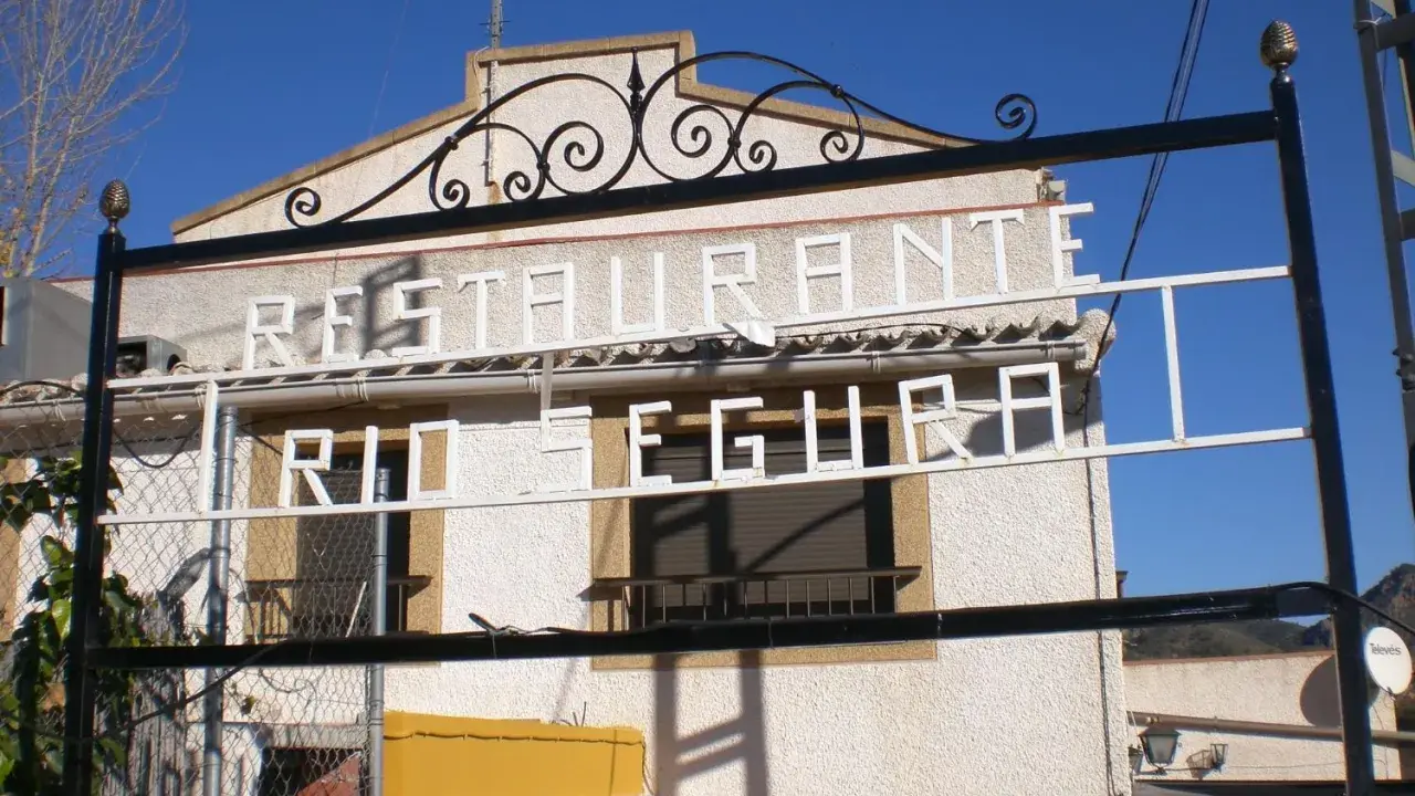 Restaurante El Gallego Elche de la Sierra, con letrero "Restaurante Río Segura" en blanco sobre fachada texturizada.
