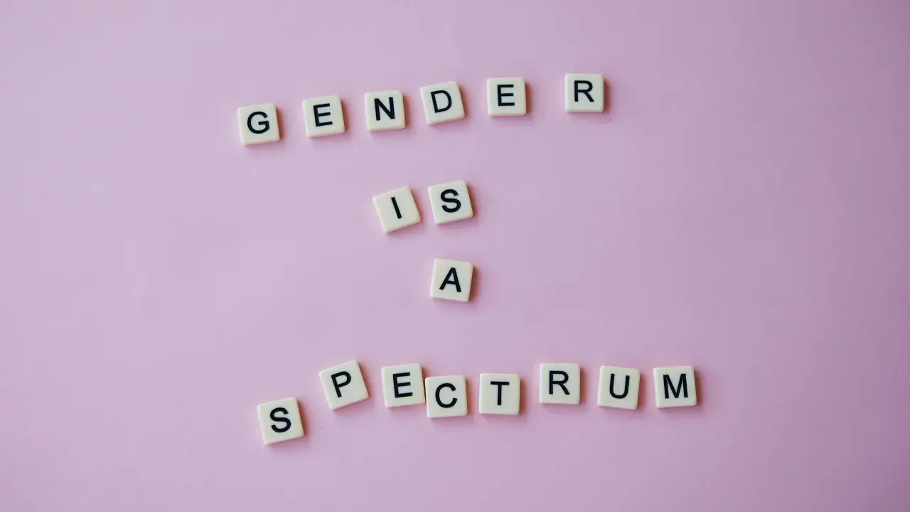 Litery układają napis "GENDER IS A SPECTRUM", podkreślając, że dysforia i niezgodność płciowa są częścią szerokiego spektrum tożsamości.