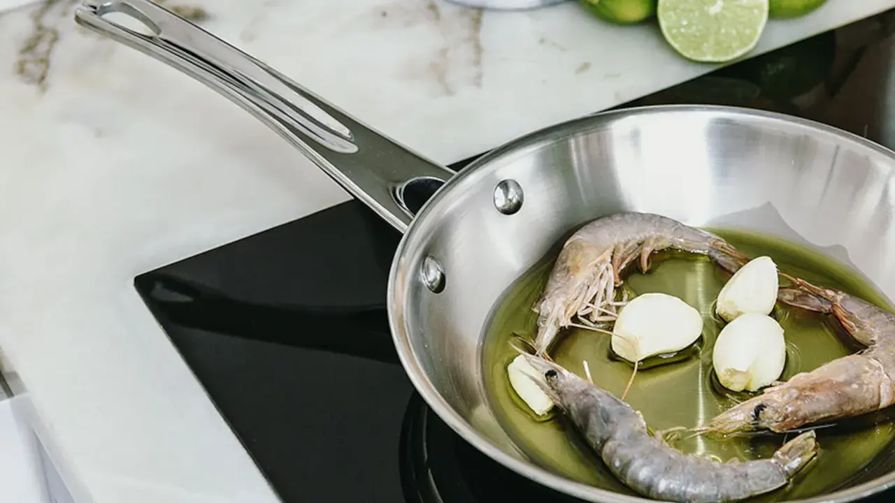 Camarones y ajo en sartén de acero inoxidable, un paso para como curar una sartén de acero inoxidable.