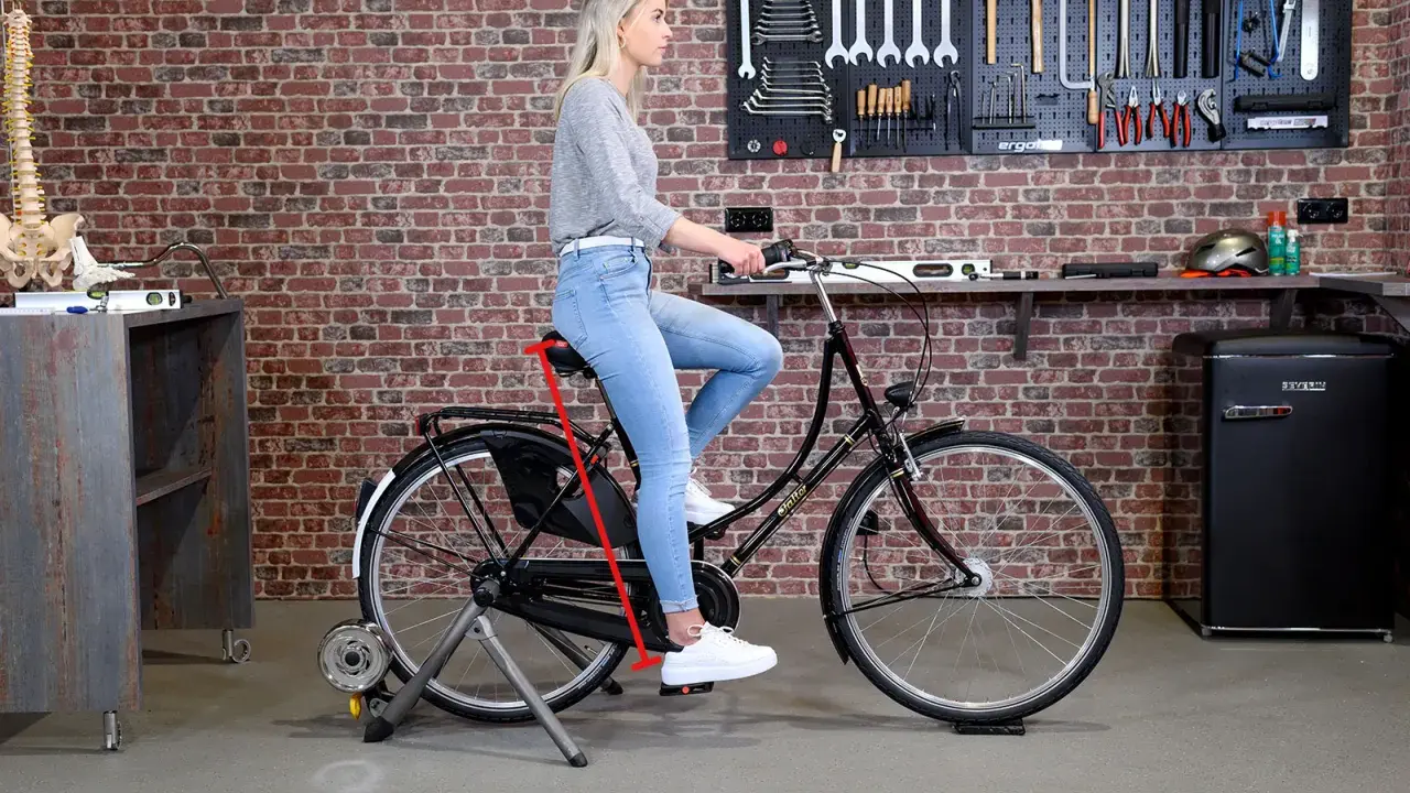 Frau sitzt auf einem Fahrrad auf einem Rollentrainer. Ein roter Pfeil zeigt die richtige Höhe des Fahrradsattels an, um den Fahrradsattel richtig einzustellen.