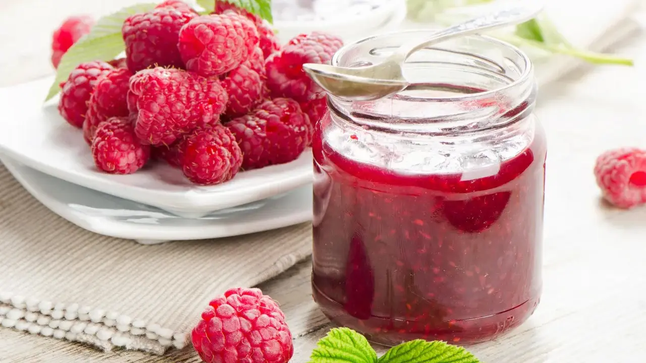 Frische Himbeeren und ein Glas selbstgemachte Himbeermarmelade. Ein einfaches Rezept für den Sommer.