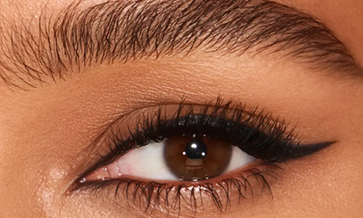 Ojo con pestaña larga y ceja poblada, delineado negro con un sutil eyeliner difuminado en el párpado superior.