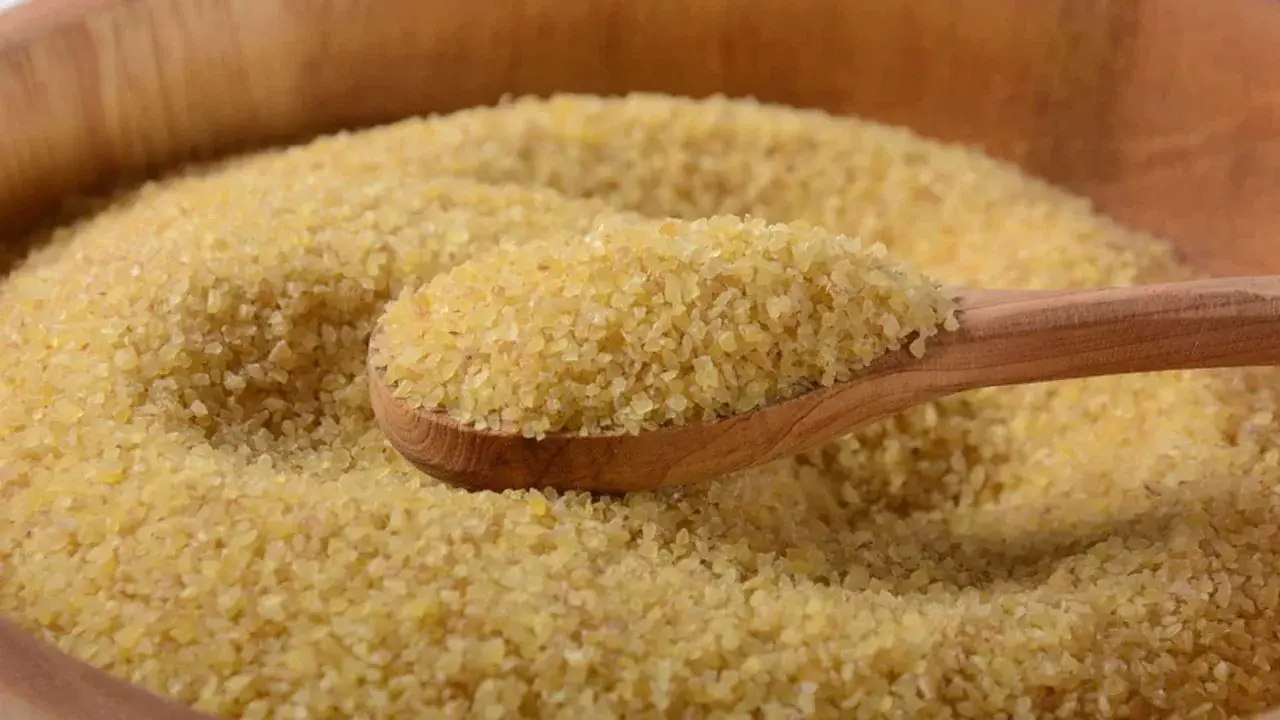 Eine Holzlöffel voller Bulgur, ein gesundes Getreide, das oft in der Ernährung während der Schwangerschaft empfohlen wird.