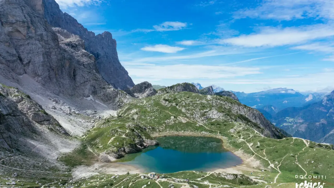 Lago di Coldai, incastonato tra le maestose vette delle Dolomiti, con sentieri che si snodano sui prati verdi.