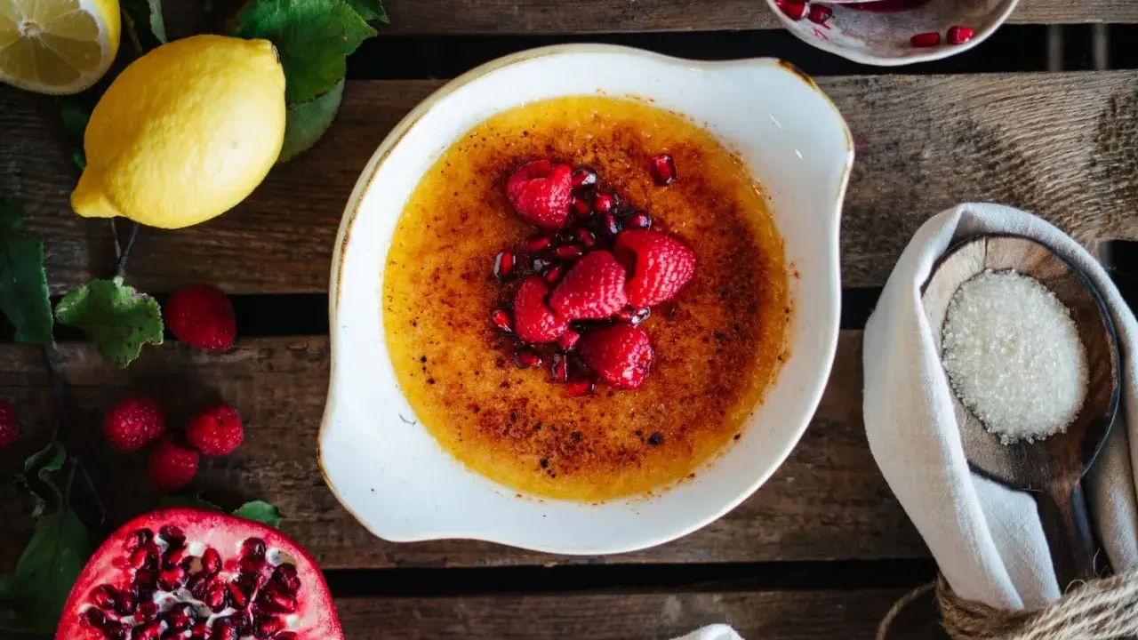 Creme Brulee mit Himbeeren und Granatapfelkernen. Dazu passen Zitronen und Zucker.