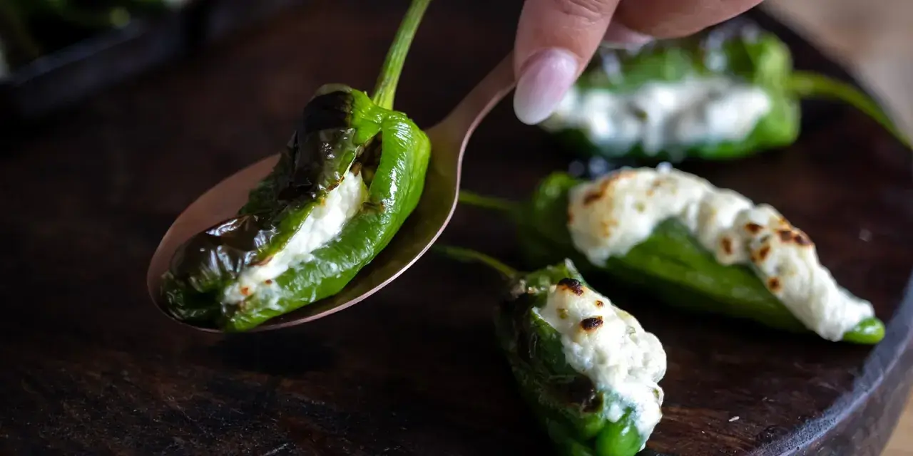 Grön paprika fylld med ost, som pimientos de padron, ligger på en sked.