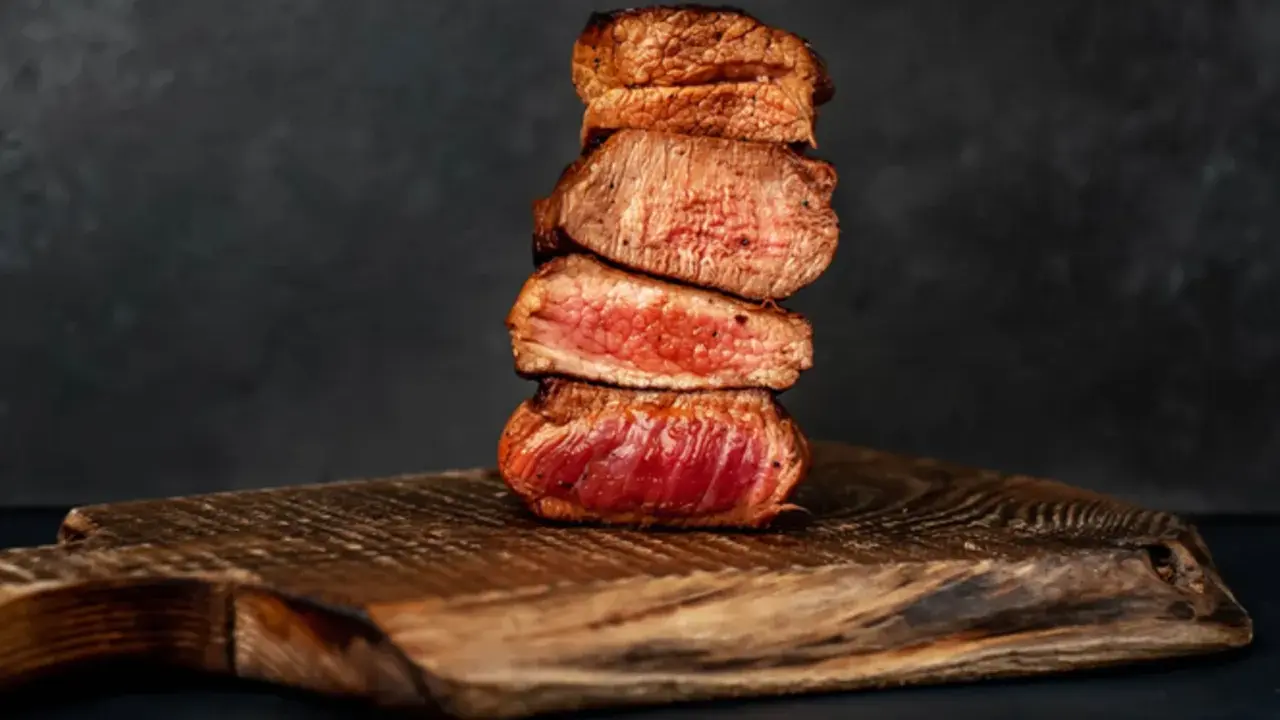 Gestapelte, saftige Steak-Scheiben, perfekt englisch gebraten, auf einem rustikalen Holzbrett.