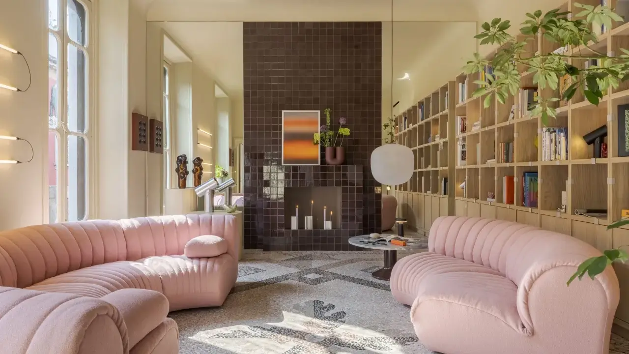Divani rosa in un luminoso open space con camino moderno e libreria a parete. Case moderne interni open space.