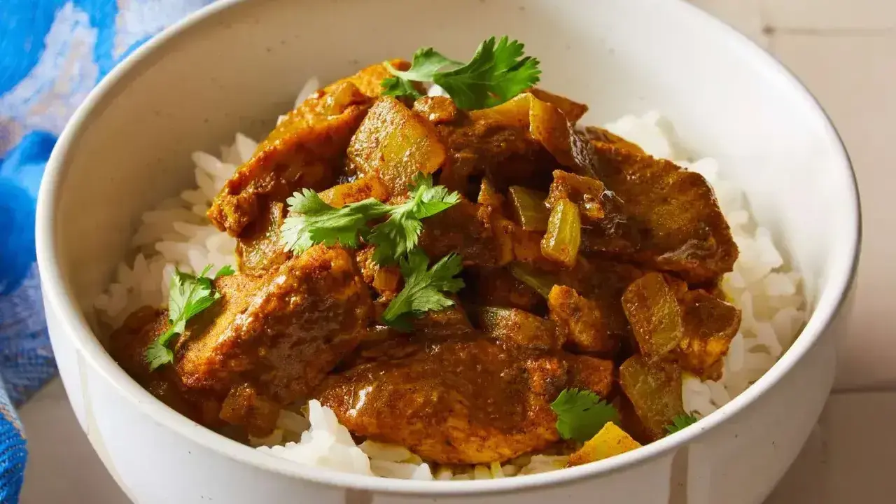 Aksamitny kurczak w sosie curry, podany na białym ryżu, z gałązkami kolendry. Idealny prosty przepis na obiad.
