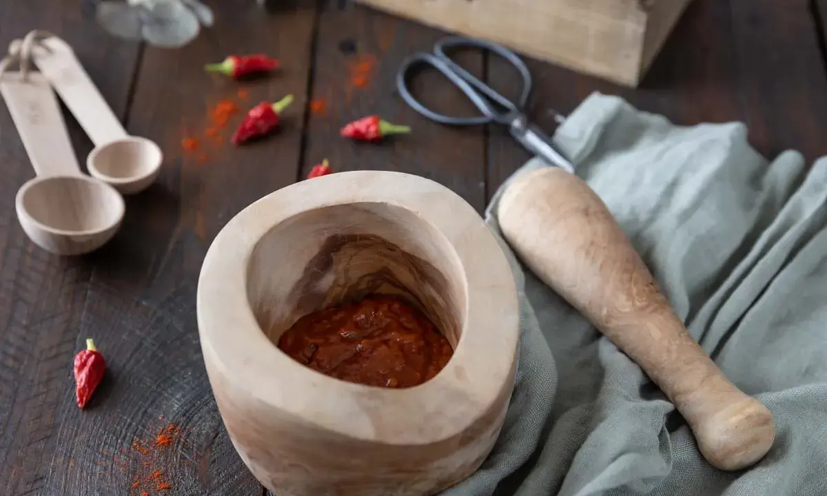 Mortier en bois avec une pâte épicée javanaise, piments rouges séchés et des cuillères en bois. Recette à venir.