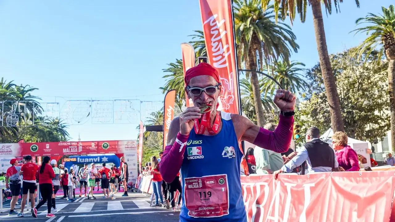 Lächelnder Läufer mit Medaille und rotem Kopftuch feiert seinen Erfolg beim Malaga Marathon.